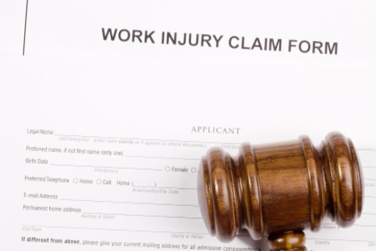 gavel lying on work injury claim form: Injury Law Colorado Workers’ Compensation Blog
